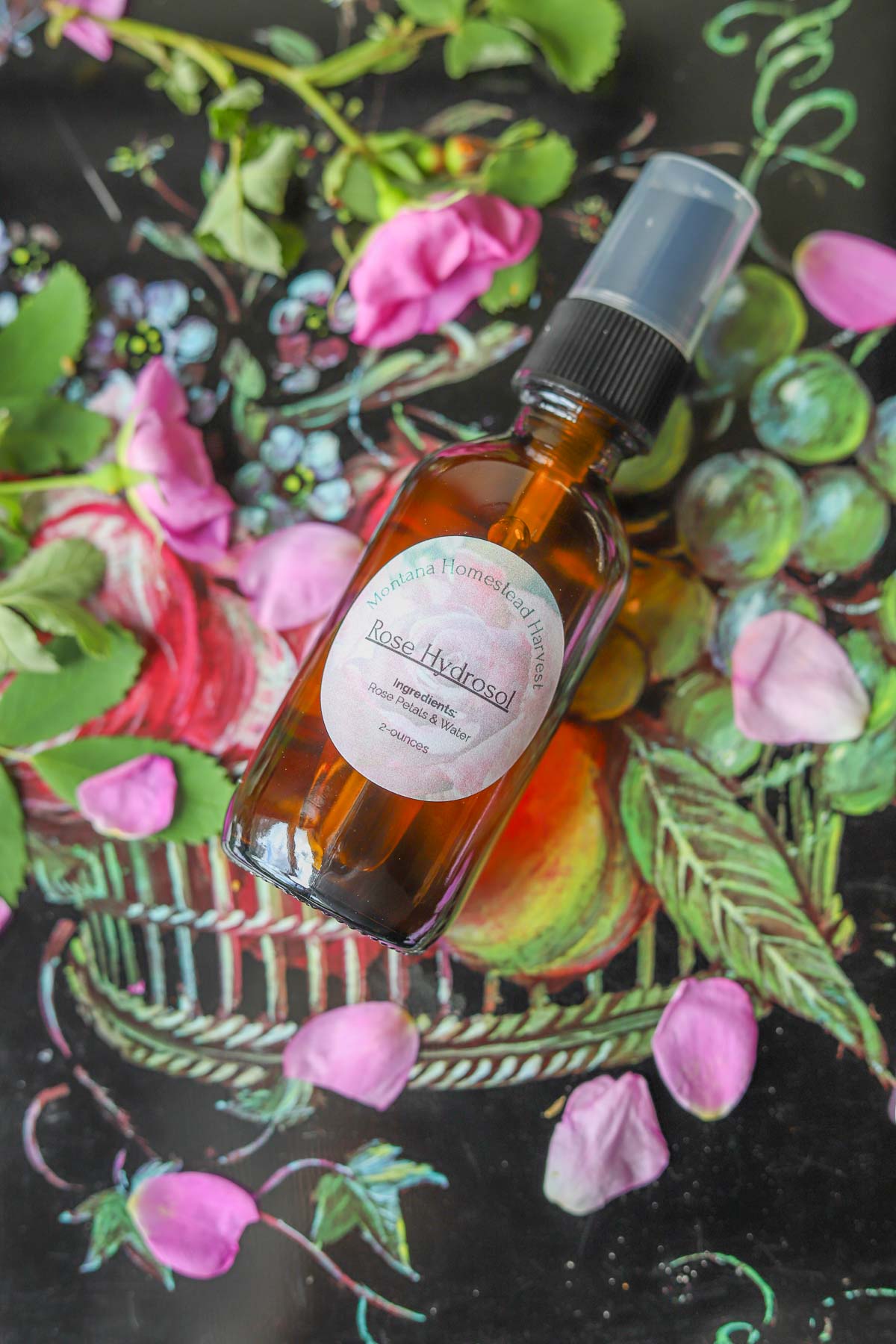rose hydrosol in a spray bottle with roses around it