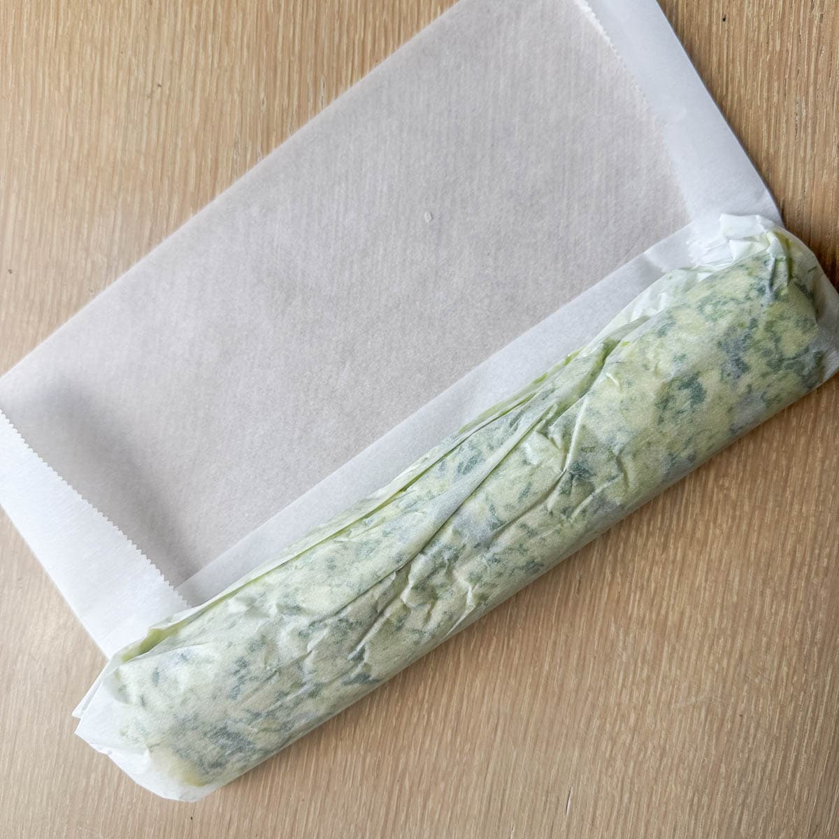 log of garlic scape butter rolled in parchment paper