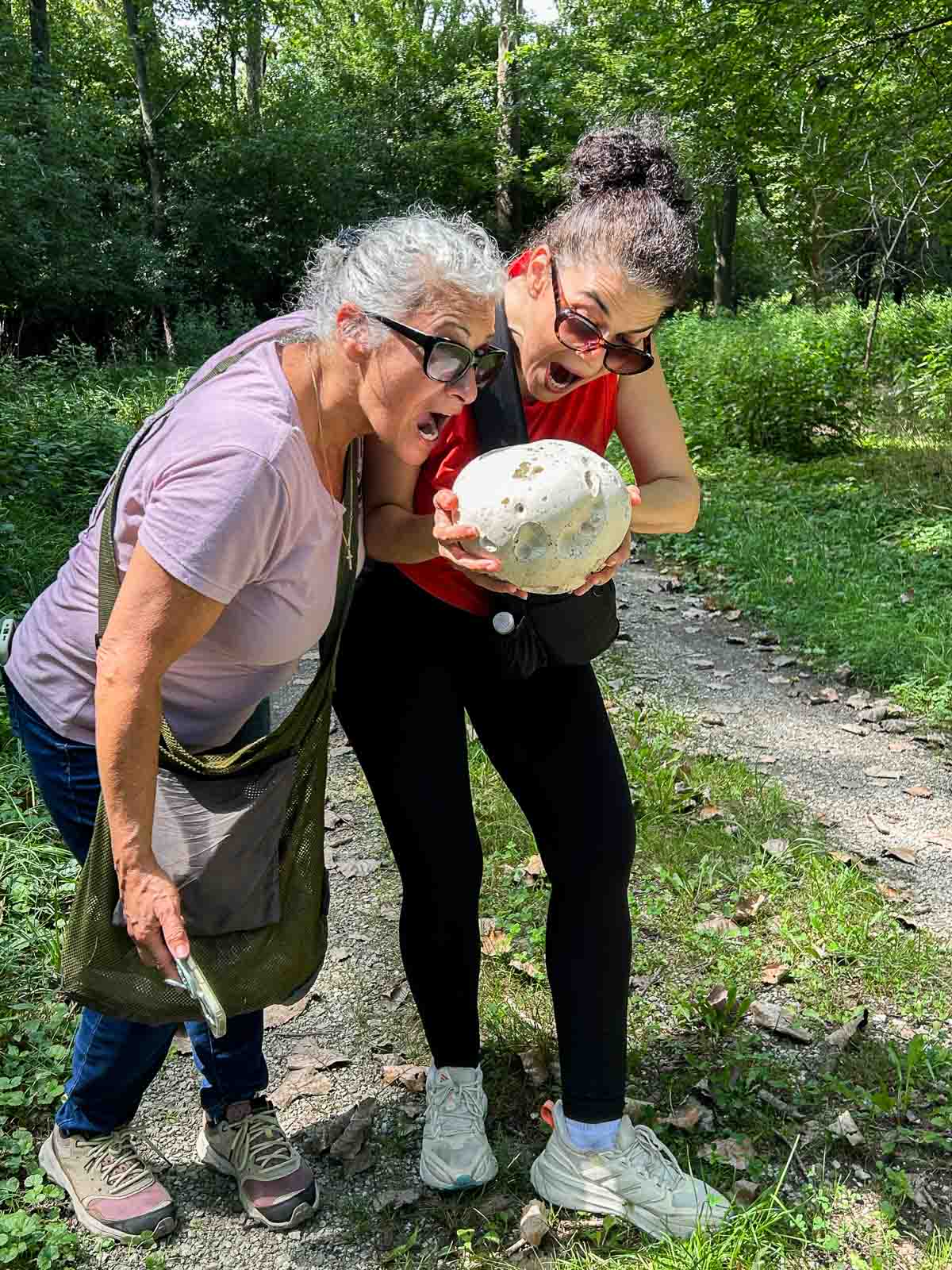 two ladies pretending to take a bite of a giant puffball mushroom