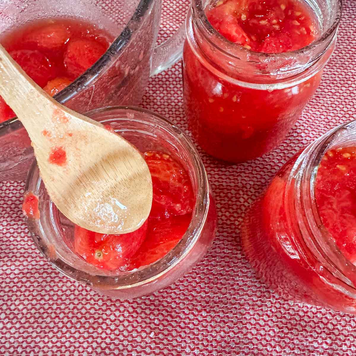 adding tomatoes to mason jars for pressure canning