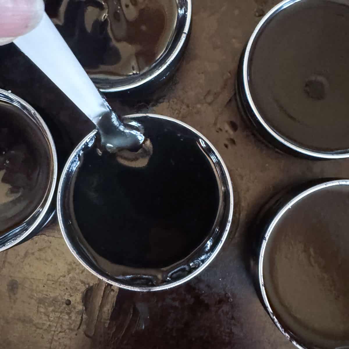 stirring black drawing salve in small tins