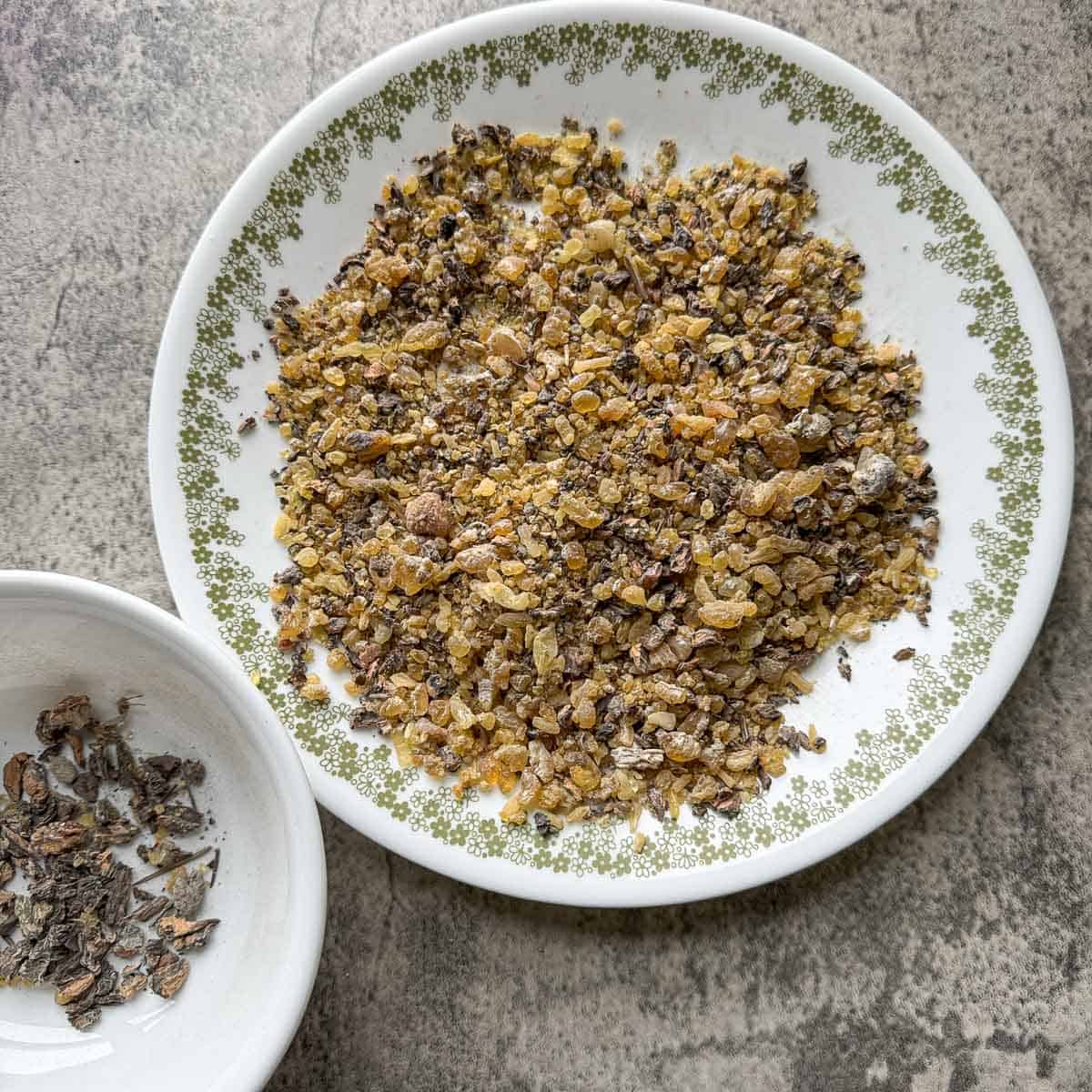 a white plate with a green border full of spruce resin and pine resin with a bowl next to it full of debris