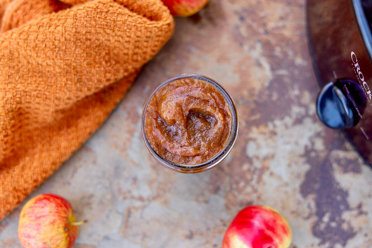 apple butter in a jar with apples and an orange towel