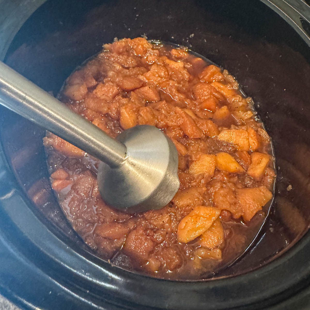 apple butter being blended with immersion blender
