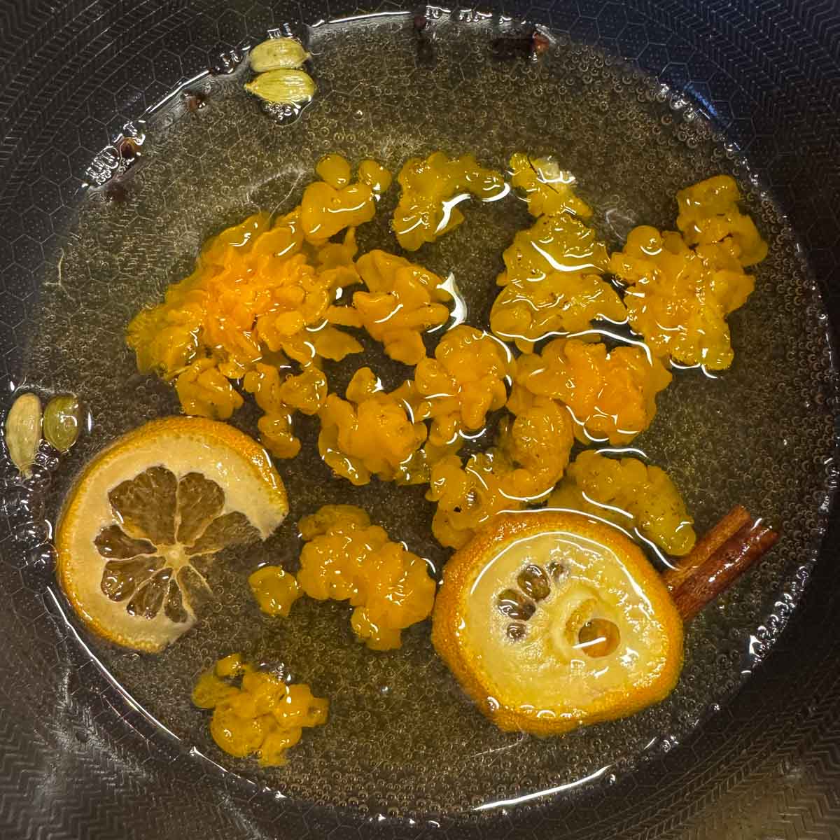 orange jelly fungus simmering in syrup with cinnamon stick and orange slices